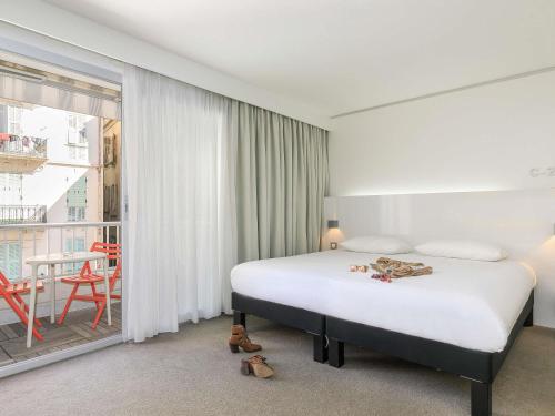 a hotel room with a bed and a balcony at Ibis Styles Menton Centre in Menton