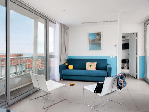 a living room with a blue couch and white chairs at Ibis Styles Menton Centre in Menton