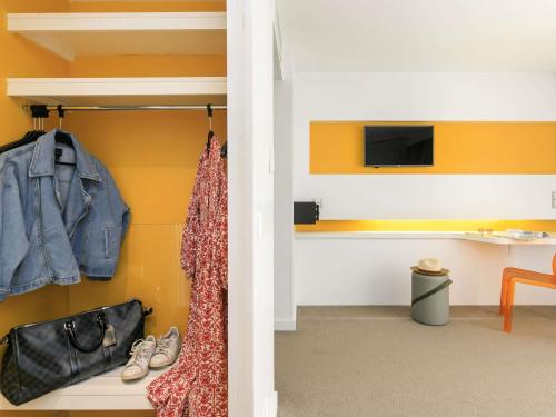 a room with yellow walls and a closet with shoes at Ibis Styles Menton Centre in Menton