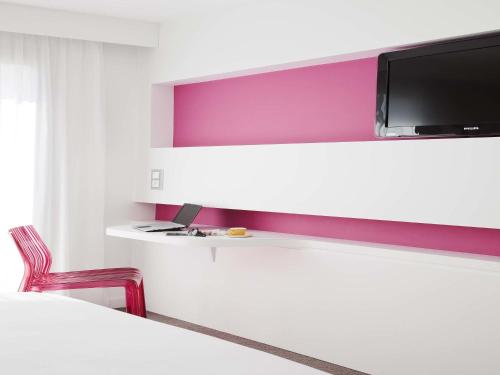 a room with a table and a tv on a shelf at Ibis Styles Menton Centre in Menton