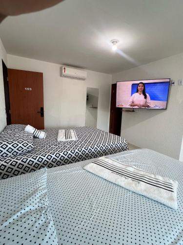 a bedroom with two beds and a flat screen tv at Suite Pajuçara in Maceió