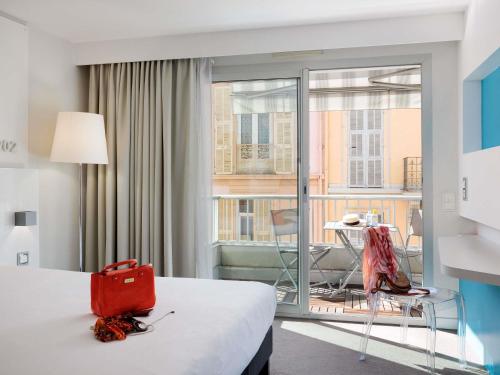 a hotel room with a bed with a red bag on it at Ibis Styles Menton Centre in Menton
