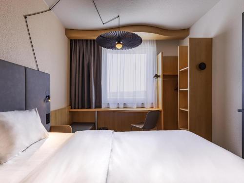 a bedroom with a bed and a desk and a window at ibis Hotel Friedrichshafen Airport Messe in Friedrichshafen