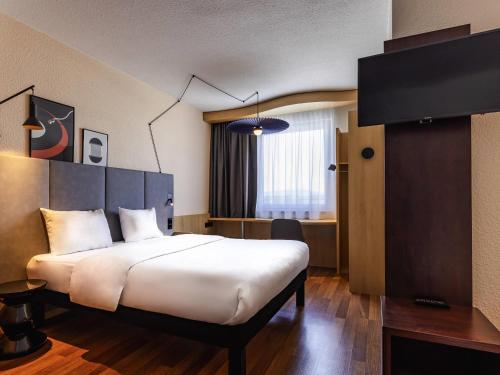 a hotel room with a large bed and a window at ibis Hotel Friedrichshafen Airport Messe in Friedrichshafen