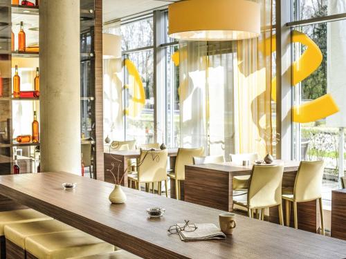 a restaurant with a table and chairs and windows at ibis Hotel Friedrichshafen Airport Messe in Friedrichshafen