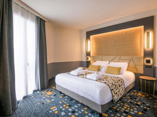 a bedroom with a large bed and a large window at Hôtel Mercure Rodez Cathédrale in Rodez