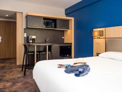 a hotel room with a bed and a table and a kitchen at Hôtel Mercure Rodez Cathédrale in Rodez