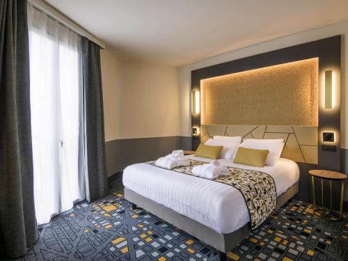 a hotel room with a bed and a large window at Hôtel Mercure Rodez Cathédrale in Rodez