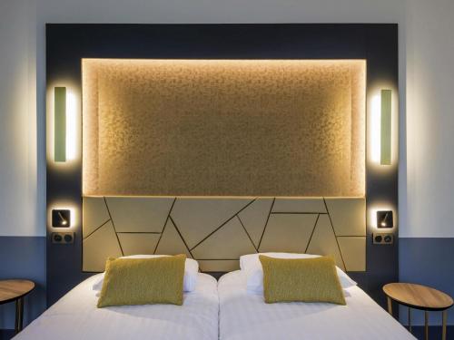 a bedroom with a white bed with two pillows at Hôtel Mercure Rodez Cathédrale in Rodez