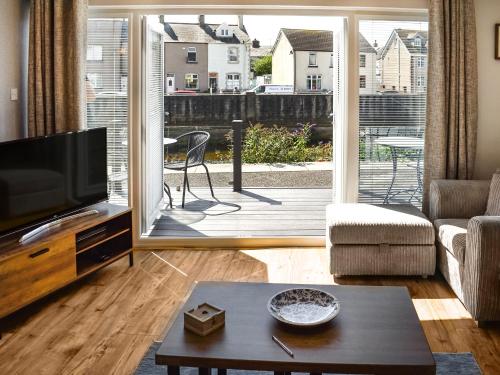a living room with a television and a sliding glass door at Kingfishers Rest in Millom