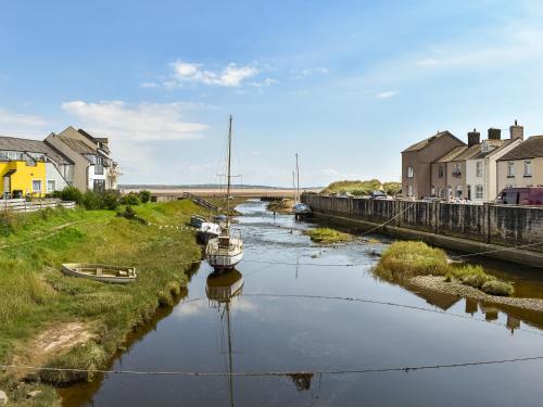 a river with boats in the water next to houses at Kingfishers Rest in Millom