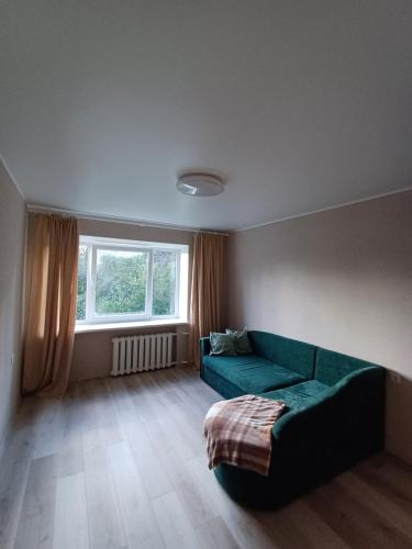 a living room with a green couch and a window at Narva mnt 26 in Jõhvi
