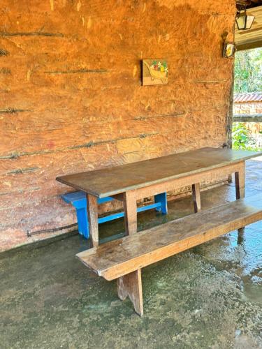 un banco de madera sentado frente a una pared en Pouso campestre Ohana para família em Tiradentes, en Tiradentes