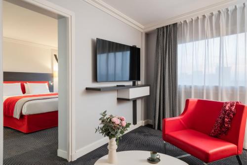 a hotel room with a red chair and a tv at Mercure Paris CDG Airport & Convention in Roissy-en-France