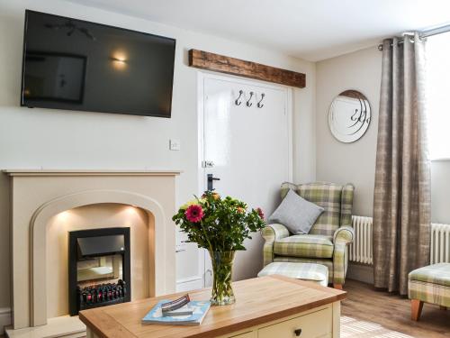 a living room with a fireplace and a vase of flowers on a table at Chapel Mouse Cottage in Cockermouth