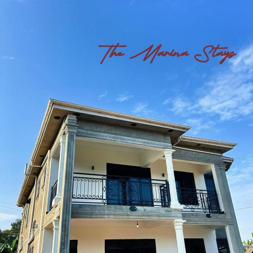 a large white house with a balcony and the words the warrior way at The Marina Stays Private Hotel Spa Entebbe in Entebbe