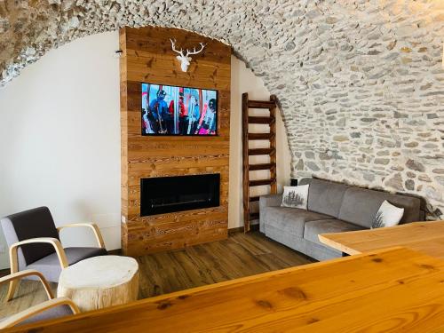 a living room with a couch and a tv on a stone wall at Mulini 22 - Eco Suite & Spa in Temù