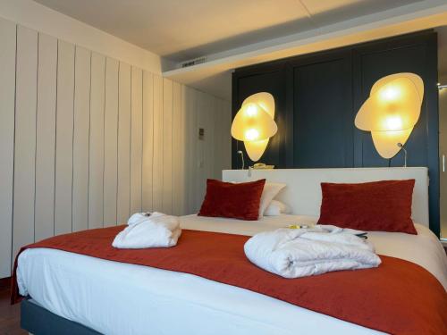 a bedroom with a large bed with towels on it at Mercure Dieppe La Présidence in Dieppe