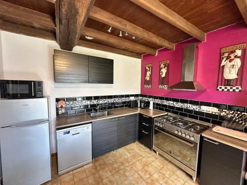 una cucina con pareti rosa ed elettrodomestici in acciaio inossidabile di Renovated French Country Bungalow for Two - A Home for Your Next Holiday a Hercé