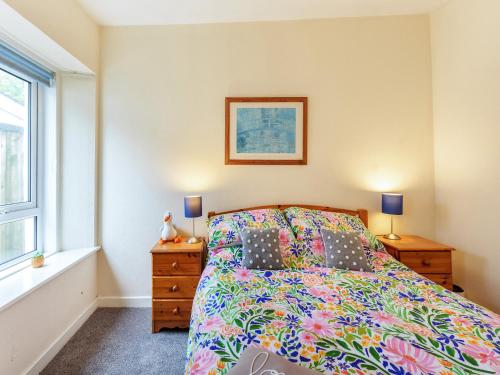 ein Schlafzimmer mit einem Bett und zwei Lampen und einem Fenster in der Unterkunft Carraig Dhubh Cottage - Uk47123 in Whiting Bay