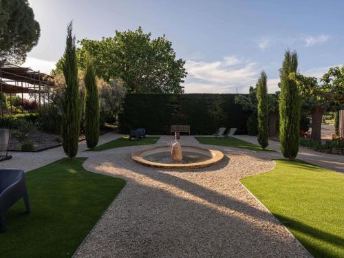 a garden with a fountain in the middle of a lawn at Mercure Aix-En-Provence Sainte-Victoire in Châteauneuf-le-Rouge