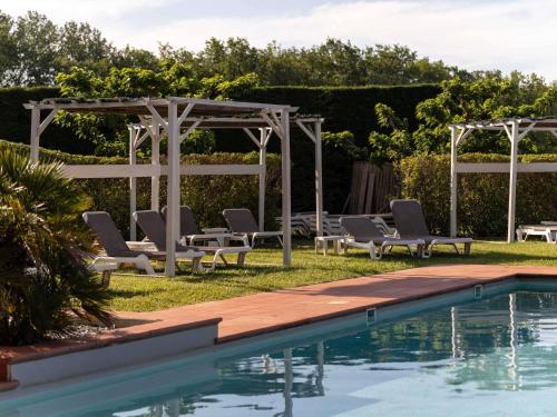 a pool with chaise lounge chairs and a pergola at Mercure Aix-En-Provence Sainte-Victoire in Châteauneuf-le-Rouge