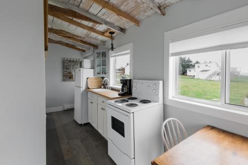 a kitchen with white appliances and a table and a window at Starfish Cottage in Peggy's Cove