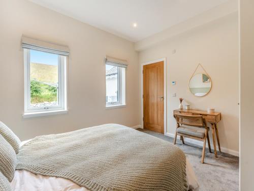 a bedroom with a bed and a desk and windows at Shoreside in Aberfeldy