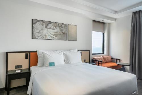 a hotel room with a large white bed and a window at Iconique Hotel Nha Trang in Nha Trang