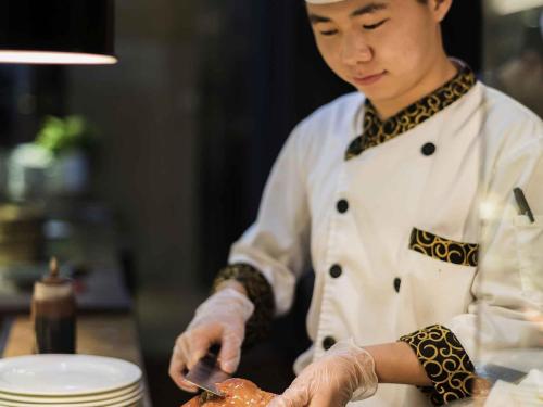 a chef preparing a dish in a kitchen at Pullman Beijing South in Daxing