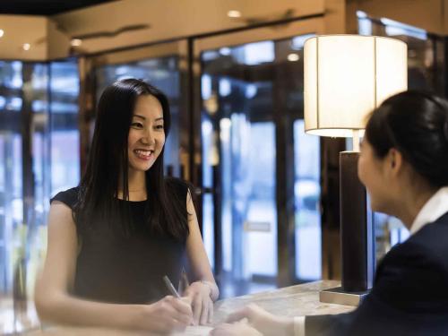 a woman sitting at a counter talking to another woman at Pullman Beijing South in Daxing