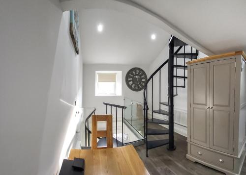 a room with a staircase and a clock on the wall at Bainbridge Ings in Hawes