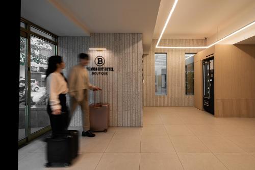 a man and woman standing in a hallway with luggage at Browndot Incheon Airport New City in Incheon