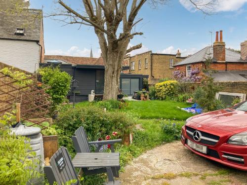 a yard with a red car parked in front of a house at The Studio in Wingham