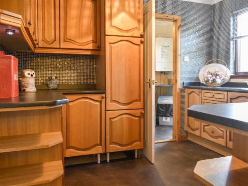 a kitchen with wooden cabinets and a counter top at Kimberley Bungalow in Alness