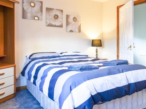 a bedroom with a bed with blue and white sheets at Kimberley Bungalow in Alness