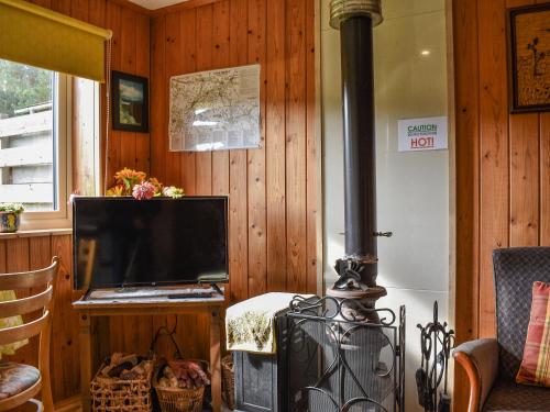 a living room with a stove and a tv at The Bothy - Ukc5785 in Nethy Bridge