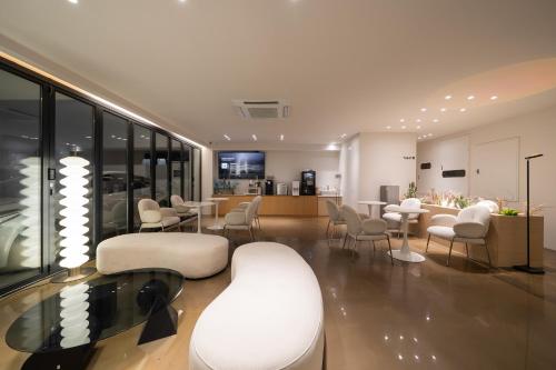 a living room with white chairs and tables and a kitchen at Browndot Incheon Airport New City in Incheon
