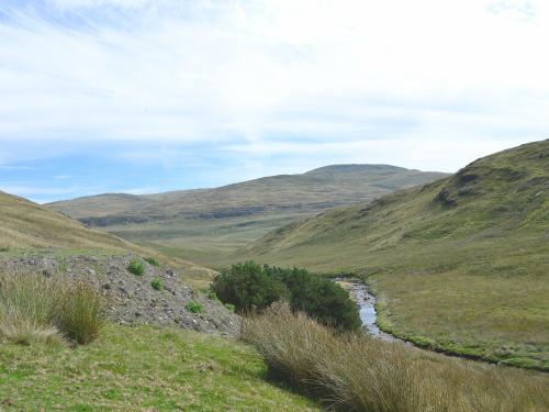 a river in a field with hills in the background at Llechwedd Mawr in Talybont