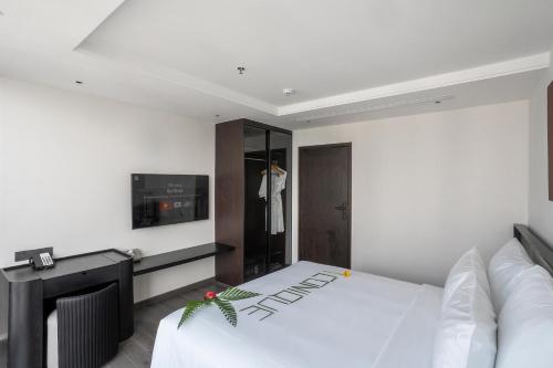 a bedroom with a white bed and a tv at Iconique Hotel Nha Trang in Nha Trang