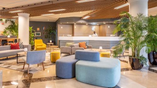 a lobby with a blue ottoman and chairs and tables at Holiday Inn Algarve Albufeira by IHG in Albufeira
