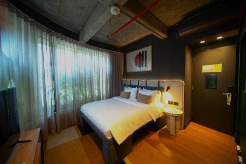 Un dormitorio con una cama y una ventana grande. en Tribe Medellín, en Medellín