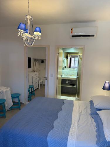 a bedroom with a blue bed and a chandelier at Pipa Magnólia Suite in Pipa