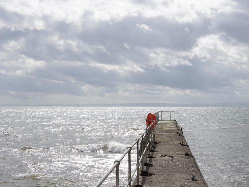 a pier sticking out into the ocean with waves at Sunrise Summerhouse in Hilton of Cadboll