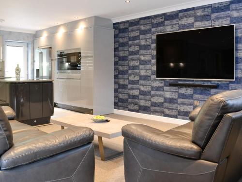 a living room with two chairs and a flat screen tv at Fernhill Cottage in Oxenhope