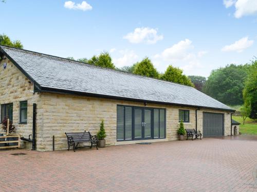 a brick building with benches in front of it at Fernhill Cottage in Oxenhope
