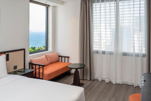 a hotel room with a bed and a chair and a window at Iconique Hotel Nha Trang in Nha Trang