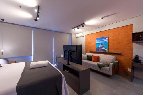 a bedroom with a bed and a tv and a couch at Excelente Flat Moderno e espaçoso no Cittyplex Osasco in Osasco