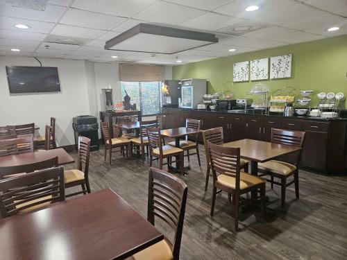 サマービルにあるSureStay by Best Western Summerville Flowertownの木製のテーブルと椅子とカウンターのあるレストラン