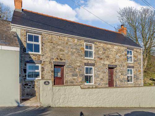 a stone house with red doors and a garage at Bon Accorde in Goodwick